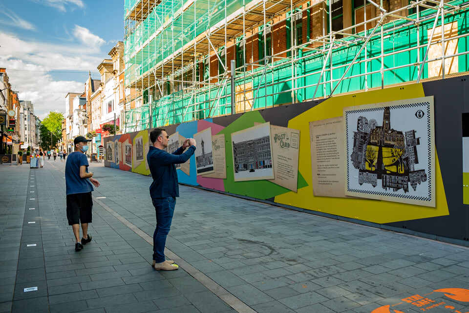 a pedestrian testing out augmented reality for artist Sarah Kirby's Street Stories artwork in Leicester