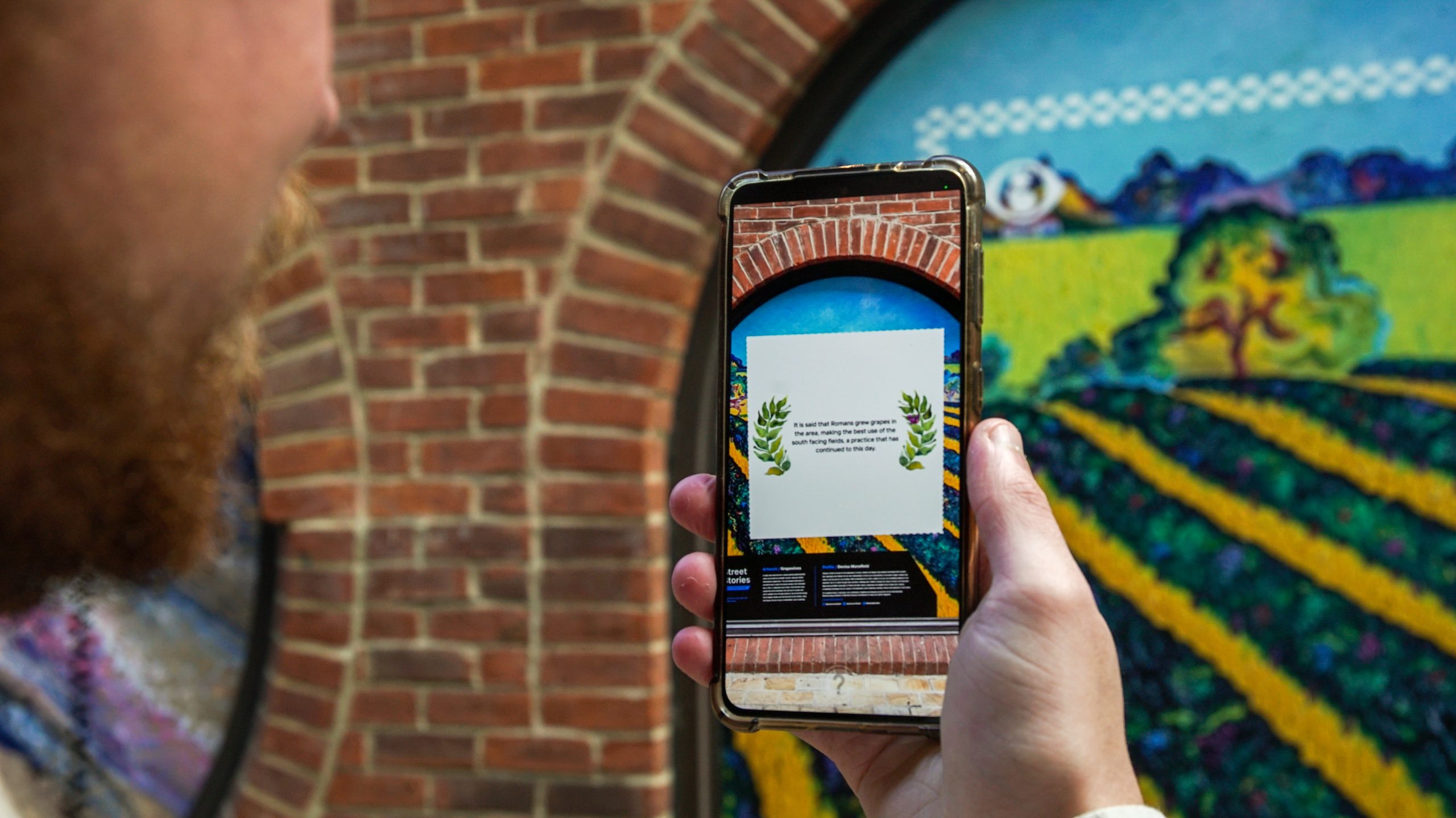 A man interacts with the Colchester AR art trail using his smartphone